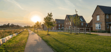 Image of houses set amongst green space, with the light shining through
