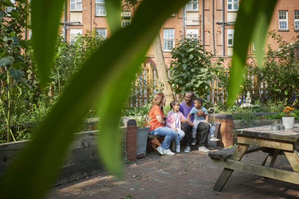 family sitting together in a park near flats