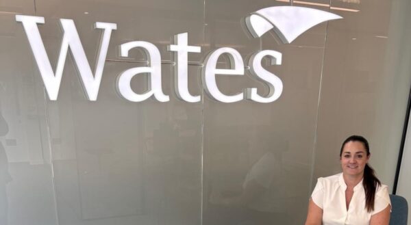 Martine, Social Value Manager, sitting in front of a Wates logo