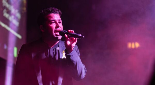 A man singing on stage at a Papyrus event